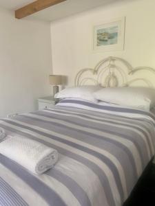 a white bedroom with a blue and white striped bed at Neptunes Rest in St Austell
