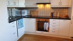 a kitchen with white cabinets and a black counter top at Studio apt in quiet residential area 20min to city centre in Oslo