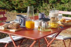 una mesa de picnic con comida, zumo de naranja y pan en Le Grand Cèdre - 2 Chambres d'hôtes - Sud Ardèche, en Bourg-Saint-Andéol