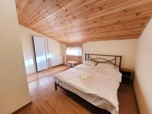 Homelike B&B في تبليسي: غرفة نوم بسرير كبير بسقف خشبي