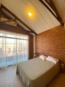 a bedroom with a bed and a brick wall at DUPLEX A PASOS DE PLAZA URQUIZA in San Miguel de Tucumán