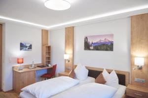 a bedroom with two beds and a desk in it at Hotel Georgenhof in Schönau am Königssee