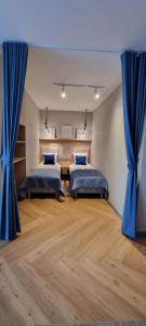 twee bedden in een kamer met blauwe gordijnen bij APARTAMENT MORZA SZUM in Sarbinowo