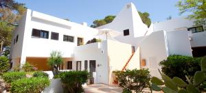 a white house with plants in front of it at Apartamentos Club Cala Azul in Cala Llenya