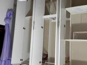 einen Schrank mit weißen Schränken und einem Spiegel in der Unterkunft Conforto com aconchego e paz in Ilha Comprida