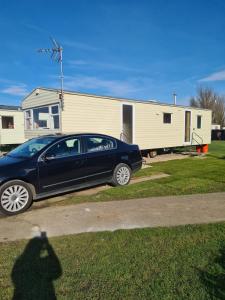 a car parked in a driveway in front of a trailer at Cosy, family caravan near the beach in Clacton-on-Sea