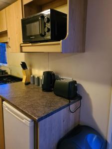a kitchen with a counter top with a microwave at Cosy, family caravan near the beach in Clacton-on-Sea
