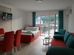 a bedroom with a bed and a living room with red chairs at Vila Leolaz in Višegrad