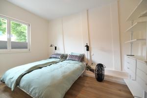 Un dormitorio blanco con una cama y una ventana. en Das schiefe Haus - Wohnung "Altstadt", en Heppenheim an der Bergstrasse