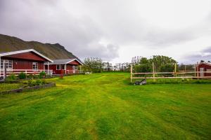 ein grüner Garten mit einem Haus und einem Zaun in der Unterkunft Móar Cottage in Akranes