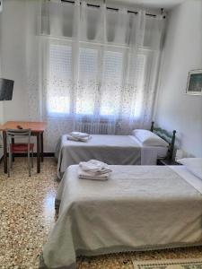 een slaapkamer met 2 bedden, een tafel en een raam bij Affittacamere Mark in Faenza