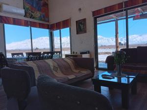 uma sala de estar com um sofá, uma mesa e janelas em Casa de Campo Finca La Angelita em Tunuyán