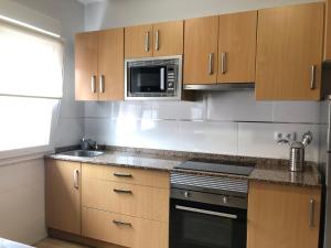 a kitchen with wooden cabinets and a microwave at Apartamento El Capricho in Cudillero