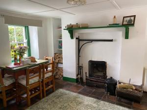 a living room with a fireplace and a table and a table and chairs at Glenaan Cottage in Cushendall