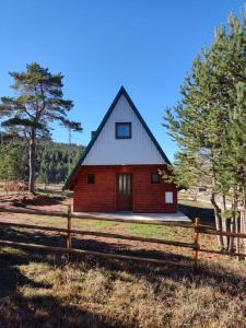 Um celeiro vermelho com uma cerca à frente. em Zabljak_vikendica em Žabljak