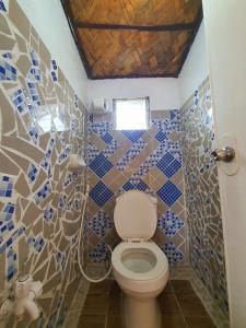 ein Badezimmer mit einem WC mit blauen und weißen Fliesen in der Unterkunft Calatagan's Bahay Kubo - with Beach Access in Batangas City