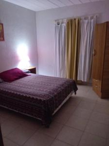 1 dormitorio con cama, lámpara y cortinas en Complejo Arena Malva en San Bernardo