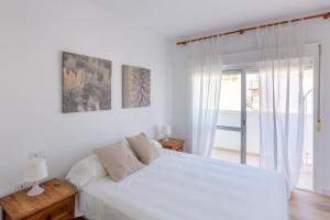 a white bedroom with a bed and a window at La Terraza de Agua Amarga in Agua Amarga