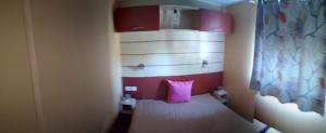 a small room with a bed with a pink pillow at Lodge das Taipas 