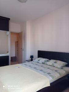 um quarto com uma cama grande com lençóis brancos e almofadas em Apartment Ana em Podgorica