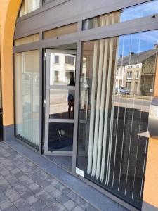 una puerta de cristal de un edificio con una persona de pie en él en Gîte Chez Aude, en Florenville