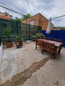 een patio met een houten bank en een parasol bij Mostar in Mostar