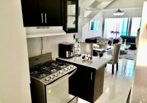 een keuken met een fornuis bovenste oven naast een woonkamer bij Bello y comodo apartment , residencial con piscina, seguridad las 24 Horas in Licey al Medio