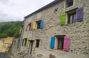 a stone building with colorful shutters on it at Inlakesh in Le Tech