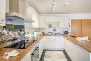 a kitchen with white cabinets and a wooden counter top at 8 Tywod Arian in Morfa Nefyn