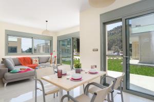 ein Wohnzimmer mit einem Tisch, Stühlen und einem Sofa in der Unterkunft Villa Paleos Sunset by Villa Plus in Ialyssos