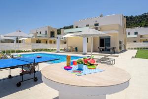 eine Terrasse mit einem Tisch und einem Pool mit einem Tisch in der Unterkunft Villa Paleos Sunset by Villa Plus in Ialyssos