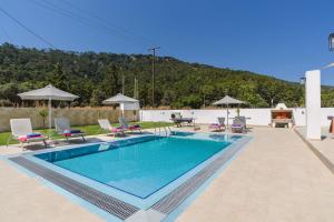 a large swimming pool with chairs and a pool at Villa Paleos Hillside by Villa Plus in Ialysos