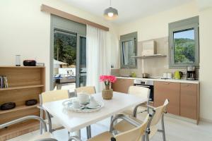 a kitchen and dining room with a white table and chairs at Villa Paleos Hillside by Villa Plus in Ialysos