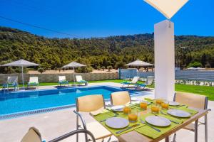 un tavolo da pranzo e sedie accanto alla piscina di Villa Paleos Evergreen by Villa Plus a Ialyssos