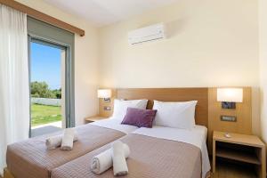 una camera con due letti e una grande finestra di Villa Paleos Evergreen by Villa Plus a Ialyssos