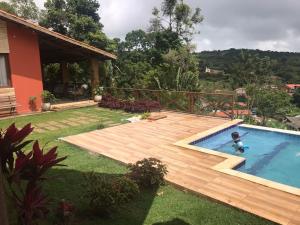 a swimming pool with a wooden deck in a yard at Sitio Maravilha in Mulungu
