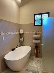 a large white tub in a bathroom with a window at 3 Bedroom Villa in Hacienda Pinilla in Tamarindo