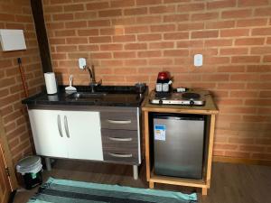 eine kleine Küche mit Spüle und Herd in der Unterkunft chalés Roma in Santo Antônio do Pinhal