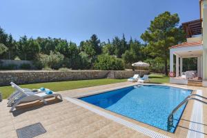 a swimming pool with chairs and a house at Villa Ermis Springs by Villa Plus in Kolimbia