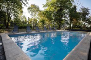 una gran piscina con sillas y árboles en Domaine Saint Laurent, en Béziers