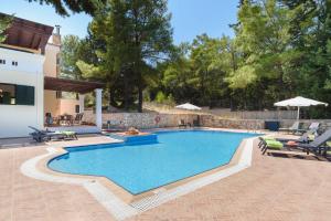 basen w ogrodzie z krzesłami i dom w obiekcie Villa Dimitra Springs by Villa Plus w Kolymbii