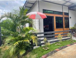 a house with a red umbrella and a palm tree at KeCai’s Place in Digos