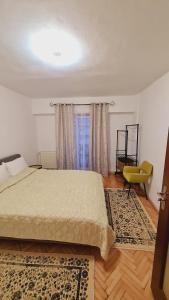 a bedroom with a bed and a yellow chair at Apartament Central in Gherla