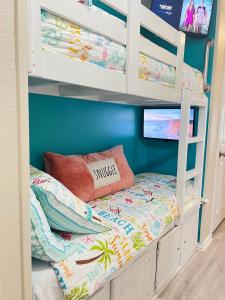 a bunk bed with a pillow and a tv on it at Sun Splashed Condo! Steps to Beach and 2 Pools Galveston Island in Galveston