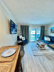 ein Wohnzimmer mit einem blauen Sofa und einem Tisch in der Unterkunft Sun Splashed Condo! Steps to Beach and 2 Pools Galveston Island in Galveston