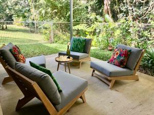 un patio con 2 sofás, una mesa y sillas en Honeybee House, en Kuranda