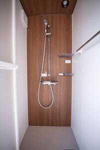 a shower in a bathroom with a wooden wall at オーシャンリゾート ザ クリフ in Shimoda