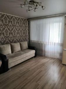 a living room with a couch and a window at Аренда квартиры город Рудный in Rudny