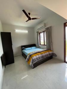um quarto com uma cama e uma ventoinha de tecto em AR Springfields(1), amidst lush green scenic view em Manipal