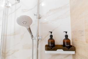 a shower with a shower head and two bottles at Люкс 1 комнатная in Rudny